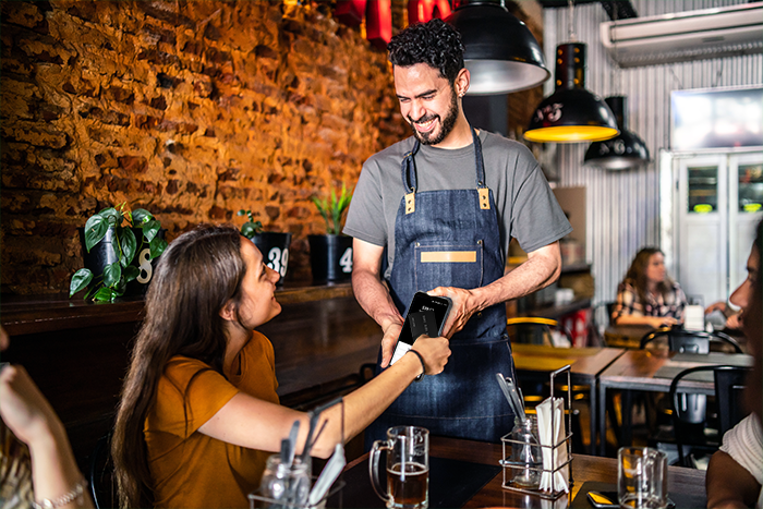 Server taking a tableside payment on a Shift4 Dine handheld